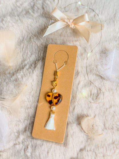 Phone charm BloomLov avec cœur à motif écaille, perles nacrées et pompon blanc