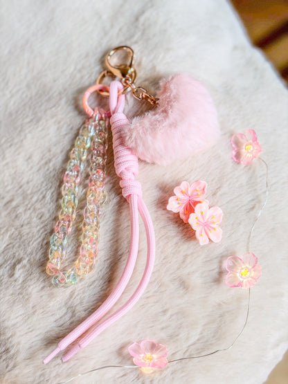 Bag charm BloomLov avec cœur en peluche rose pâle, chaîne transparente irisée et long cordon rose

