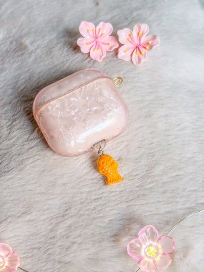 Bouchon anti-poussière taiyaki BloomLov présenté sur un boîtier d’écouteurs avec coque rose nacrée
