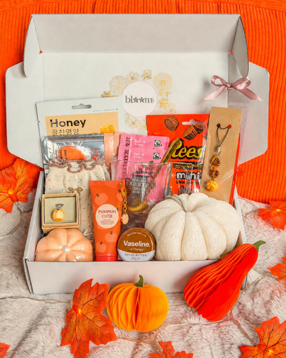 Box cocooning BloomLov ouverte avec masque visage, chaussettes, tasse, chocolats et accessoires citrouille.