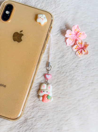 Phone charm BloomLov avec lapin blanc, fraise rose et perle cœur, accroché à une coque de téléphone - modèle aléatoire