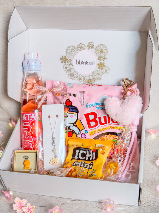 Kawaii Asia Food Box BloomLov ouverte avec nouilles coréennes, Ramune, crackers et accessoires kawaii roses

