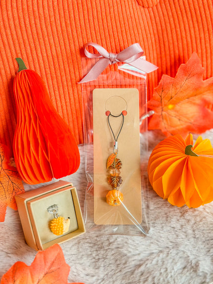 Phone charm citrouille et bouchon anti-poussière hérisson BloomLov présentés parmi des décorations d’automne
